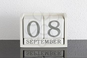 White block calendar present date 8 and month September on white wall background