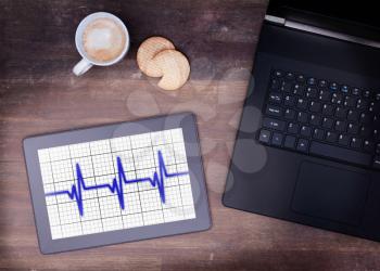 Electrocardiogram on a tablet - Concept of healthcare, heartbeat shown on monitor - blue