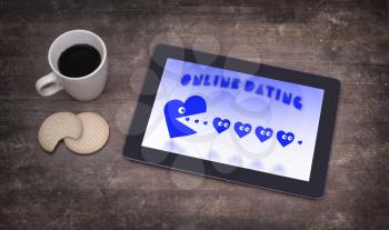 Online dating on a tablet - concept of love, blue pacman eating hearts