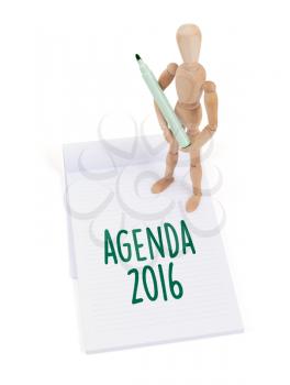 Wooden mannequin writing in a scrapbook - Agenda 2016