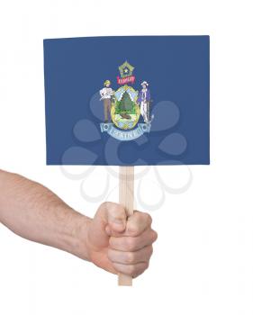 Hand holding small card, isolated on white - Flag of Maine