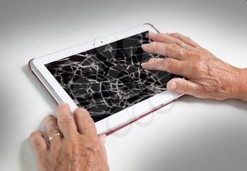 Senior lady with tablet, cracked screen, concept of insurance