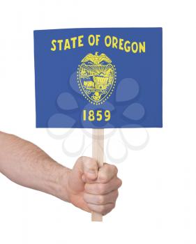 Hand holding small card, isolated on white - Flag of Oregon