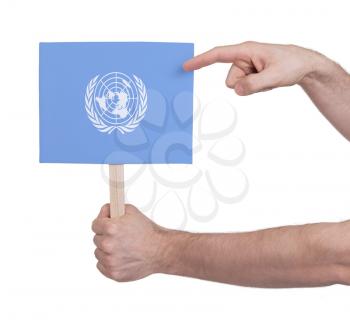 Hand holding small card, isolated on white - Flag of the UN