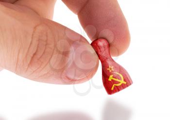 Hand holding wooden pawn with a flag painting, selective focus, USSR