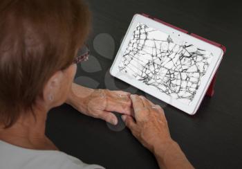 Senior lady with tablet, cracked screen, concept of insurance