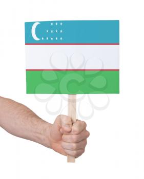 Hand holding small card, isolated on white - Flag of Uzbekistan