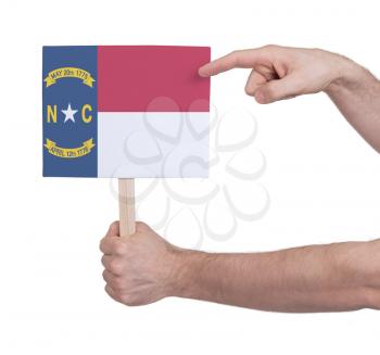 Hand holding small card, isolated on white - Flag of North Carolina