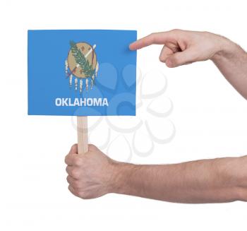 Hand holding small card, isolated on white - Flag of Oklahoma