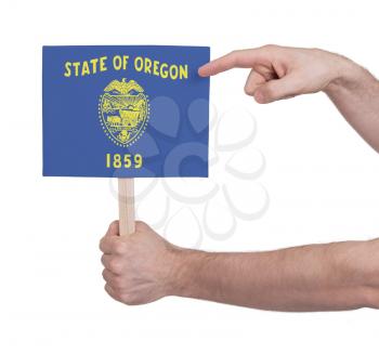 Hand holding small card, isolated on white - Flag of Oregon