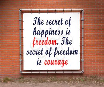 Large banner with inspirational quote on a brick wall - Secret of happiness