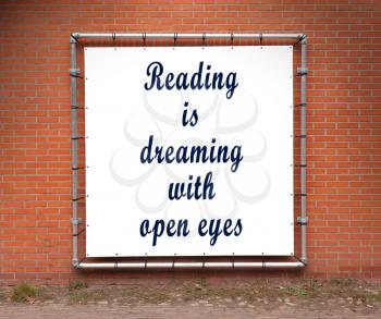 Large banner with inspirational quote on a brick wall - Reading is dreaming with open eyes