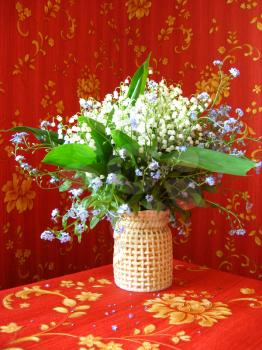 Beautiful bouquet of lilies of the valley and blue flowers on a red background