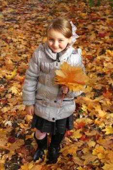 little girl with yellow leaf in the park in autumn