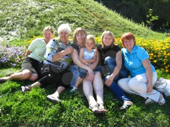 women of three generations sitting on the green grass