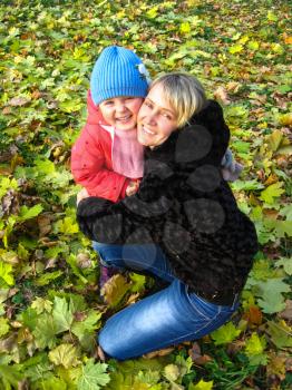 Happy and smiling mother and her child in park in the autumn