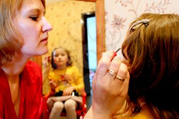 image of mother makes up daughter's face before a mirror