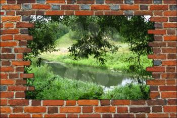 hole in the brick wall and view to summer river with green leaves of willow