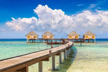 MALDIVES - JUNE 24, 2018: Water Villas (Bungalows) and wooden bridge at Tropical beach in the Maldives at summer day