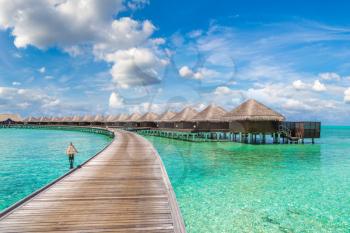 MALDIVES - JUNE 24, 2018: Water Villas (Bungalows) and wooden bridge at Tropical beach in the Maldives at summer day