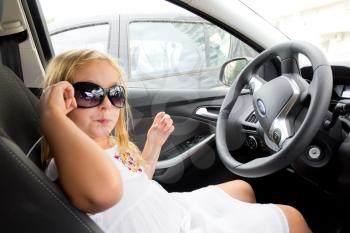 Cute girl driving car in sun glasses
