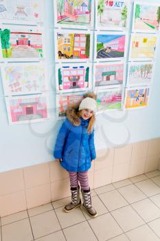 Cute girl near wall with children drawings