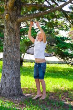 Cute girl in summer try to jump on tree