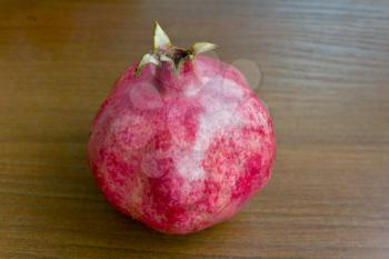 Photo of one pomegranate on brown wooden background