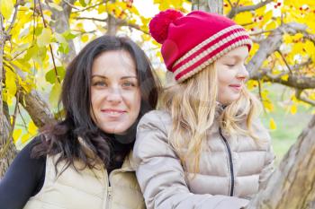 Photo of mother and daughter on spreading tree in autumn
