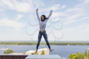 Photo of jumping young woman on river background