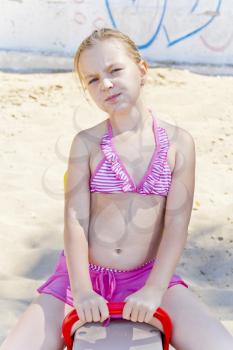 Chewing girl at playground on the beach