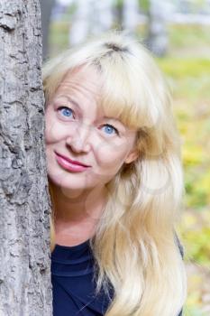 European blond woman with long hair on tree background