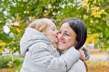 Photo of kissing mother and daughter in autumn