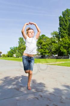 Cute girl with blond hair jumping on one leg