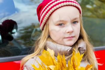 Portrait of cute smiling girl in red hat in autumn
