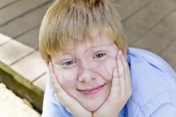 Portrait of cute blond boy sitting out door