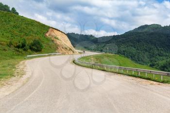 Dangerous curve mountain road in green summer