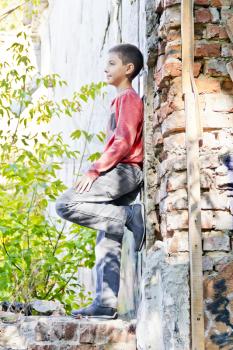 Cute boy standing near old brick wall in summer