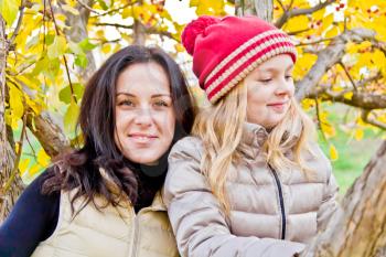 Photo of mother and daughter in autumn sitting on tree