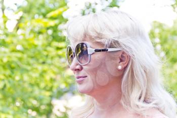 Blond woman in sunglass on green background