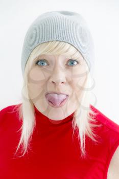 Vertical portrait blond woman in grey hat with put out tongue