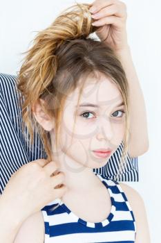 Cute girl playing with blond long hair standing near white wall hairstyle