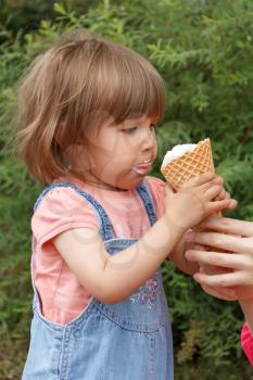 Cute baby girl are eating icecream in summer with put out tongue