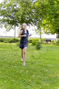 Cute running European girl with disheveled hair in green park