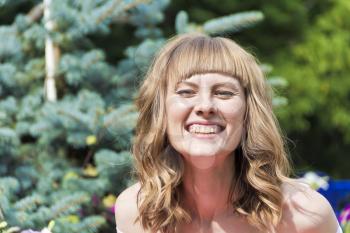 Portrait of laughing young woman with blond hair on summer background