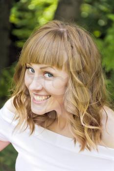 Portrait of laughing young woman with blond hair on summer background