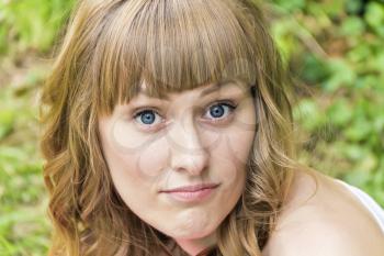 Horizontal portrait of young woman with big bulging blue eyes on summer background