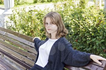 Beautiful girl fourteen years old are sitting on the bench