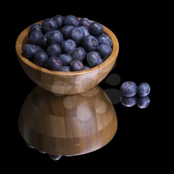 Blueberries in wooden bowl on a mirror. Isolated on black.