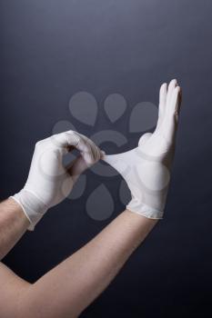 Male hands in golves. Doctor or nurse putting on latex gloves. Sanitary, healthcare, medical clothing. Dark background